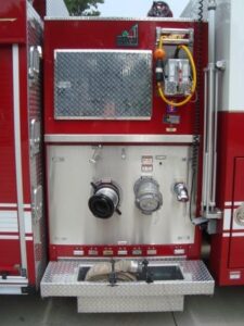 This is the passenger side pump panel.  A 5" intake and a 5" discharge are located on this side.  An electric reel and junction box are above the panel.  A removable tri-pod light is to the right of the panel.